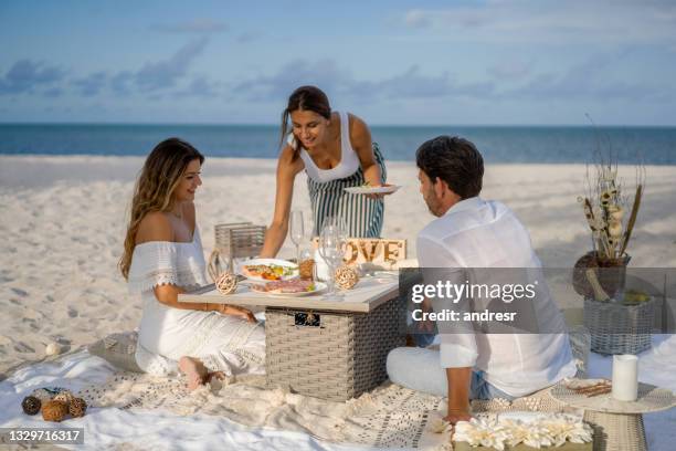 waitress serving food to a happy couple on a romantic date at the beach - service anniversary stock pictures, royalty-free photos & images