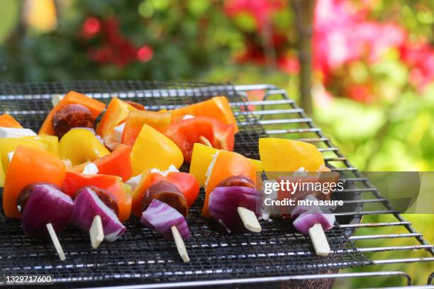 image of portable, charcoal barbecue in garden, kebabs being cooked outdoors on a metal grill, diced feta cheese, red onion, chorizo sausage, orange and yellow peppers, focus on foreground - red hot summer party stock pictures, royalty-free photos & images