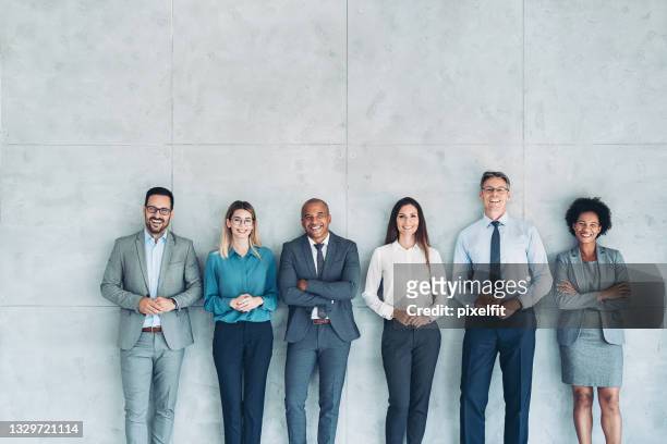 group of business persons standing against a wall - professional occupation stock pictures, royalty-free photos & images