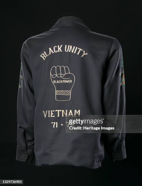 Black jacket probably worn by an African-American soldier during the Vietnam war. The back features discolored white embroidery. Image of a fist...
