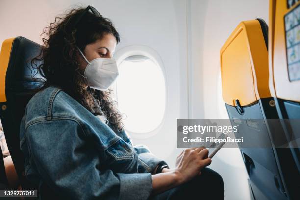 woman on an airplane is texting on her smart phone - covid 19 mask stock pictures, royalty-free photos & images