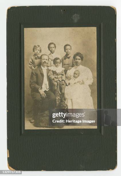 Black and white, formal family portrait photograph of Senator Henry Hall Falkener and his family in a black, paper mat. Senator Falkener is seated on...