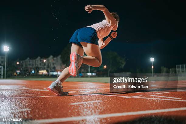 side view aerodynamic asian chinese female athletes sprint running at track and run towards finishing line at track and field stadium track rainy night - female muscle calves stock pictures, royalty-free photos & images