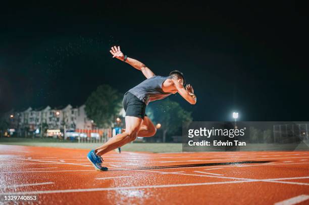 side view aerodynamic asian chinese male athletes sprint running at track and run towards finishing line at track and field stadium track rainy night - forward athlete stock pictures, royalty-free photos & images