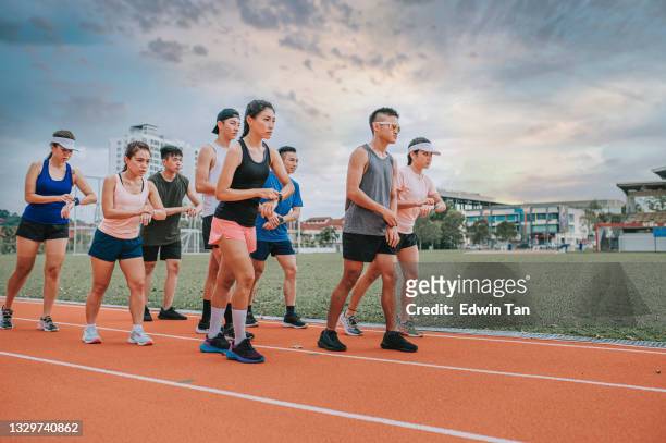 los atletas chinos asiáticos que se alinean para prepararse comienzan a cronometrar usando el tiempo de reloj inteligente del trazador de fitness antes de correr en la pista y correr hacia la línea de meta por la mañana en el estadio de atletismo - lining up sports activity fotografías e imágenes de stock