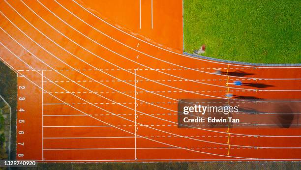 directly above drone point of view asian chinese male athlete running at men's track rainy late evening in stadium - corrida de ponto imagens e fotografias de stock