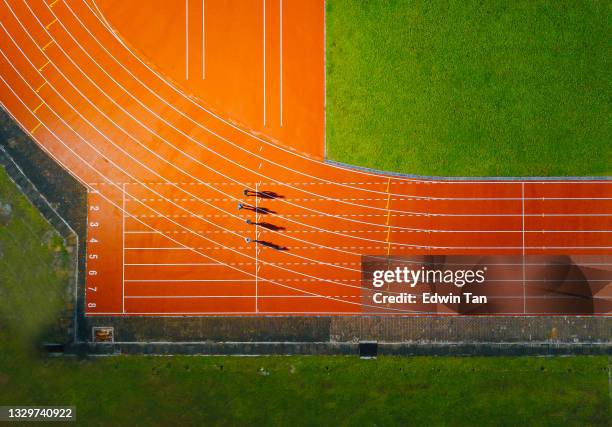 direkt über drohnensicht asiatischer chinesischer männlicher athlet läuft auf männerbahn regnerisch am späten abend im stadion - race track stock-fotos und bilder