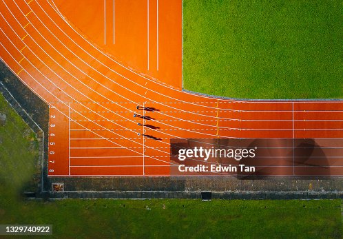 Directly above drone point of view asian chinese male athlete running at men's track rainy late evening in stadium Directly above drone point of view asian chinese male athlete running at men's track rainy late evening in stadium