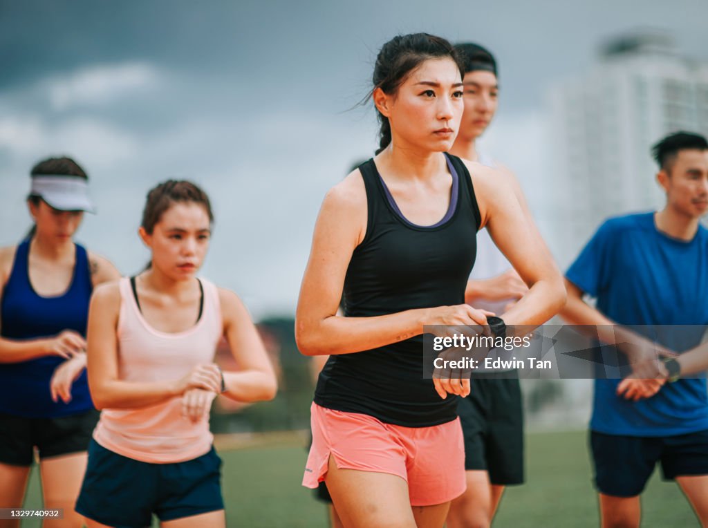 Asian chinese athletes lining up getting ready start timing using fitness tracer smart watch time before running at track and run towards finishing line in the morning at track and field stadium