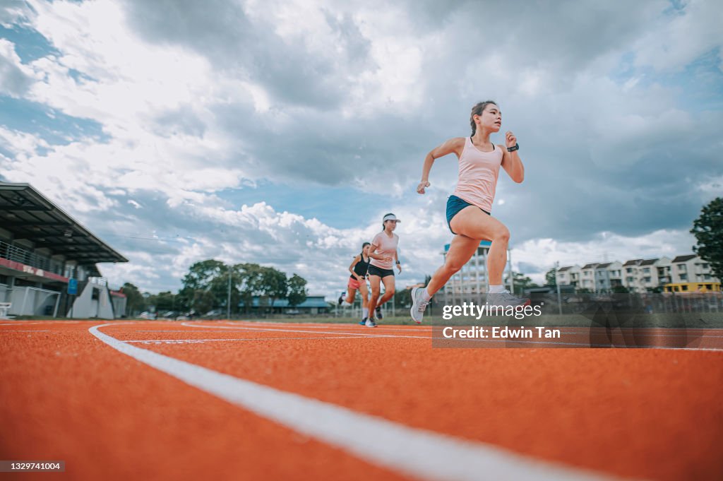 Asiatische chinesische Athletinnen laufen am späten Abend im Stadion regnerisch auf der Bahn