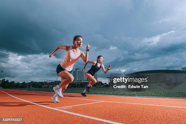 asiatische chinesische athletinnen laufen am späten abend bewölkt auf der bahn im leichtathletikstadion - scoring run stock-fotos und bilder