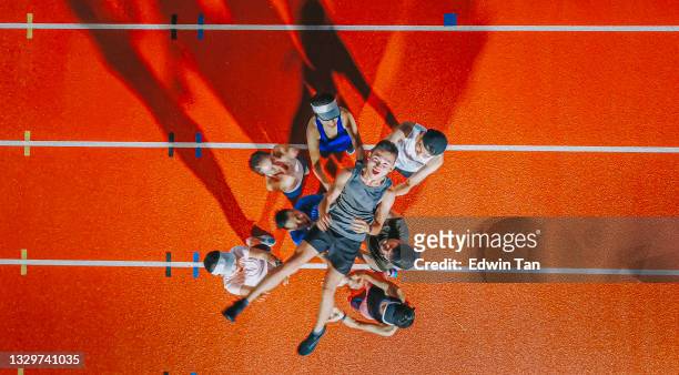 directly below drone point of view asian chinese athletes cheering throwing lift up their captain winner mid air at storm cloud late evening in stadium - team captain sport stock pictures, royalty-free photos & images