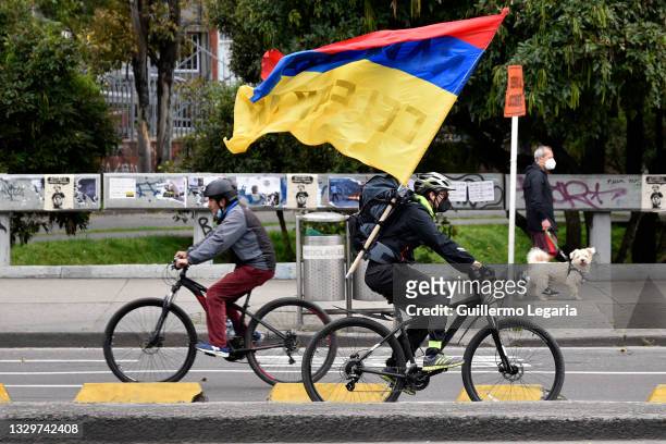 Person rides a bicycle holding a Colombian flag upside down as a symbol of protest against the government during an anti-government protest on July...