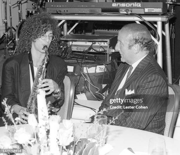 American smooth jazz saxophonist Kenny G plays as American record producer, A&R executive, music industry executive, and lawyer Clive Davis listens...