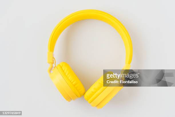 yellow wireless headphones on a gray blue background - headphone stock-fotos und bilder