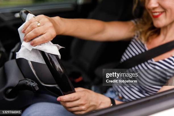 woman wiping a steering wheel with a disinfecting wipe - cleaning inside of car stock pictures, royalty-free photos & images