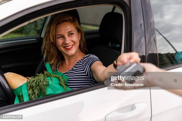 paying for her curbside pickup with a credit card - drive through stock pictures, royalty-free photos & images