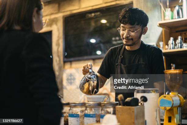 a barista pouring hot water for coffee - barista coffee restaurant stockfoto's en -beelden