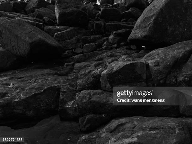 a black stony beach by the sea - black stone background imagens e fotografias de stock