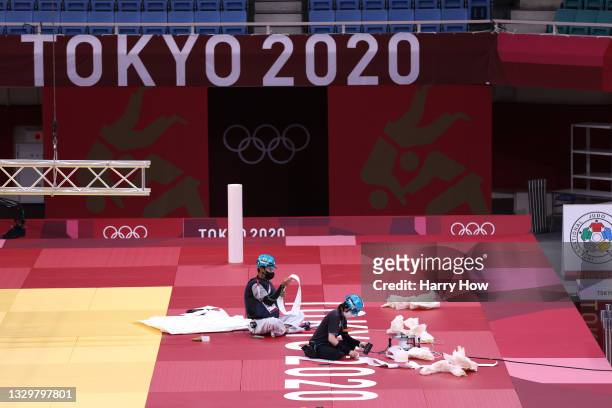 Workers prepare the Tokyo 2020 logo on the field of play for judo at the Nippon Budokan ahead of the Tokyo 2020 Olympic Games on July 21, 2021 in...
