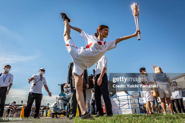 Torch bearer poses for photographs during the Olympic Torch Relay Celebration event on July 21, 2021 in Tokyo, Japan. As the Olympic torch relay...