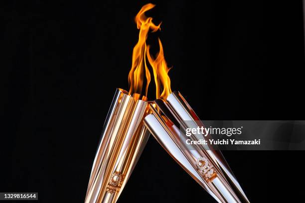 Torch bearers exchange the flame during the Olympic Torch Relay Celebration event on July 21, 2021 in Tokyo, Japan. As the Olympic torch relay makes...