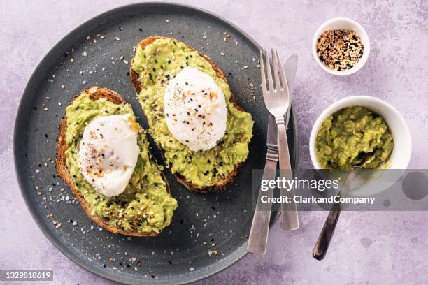 tostadas de aguacate con huevos benedict y semillas de sésamo tostadas. - escalfado fotografías e imágenes de stock