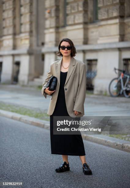 Sophie van Daniels is seen wearing olive blazer ARKET, black dress COS, shoes ARKET, bag Bottega Veneta on July 20, 2021 in Berlin, Germany.