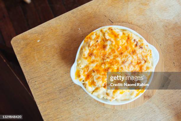 baked macaroni cheese dish on a timber table - macaroni stock pictures, royalty-free photos & images