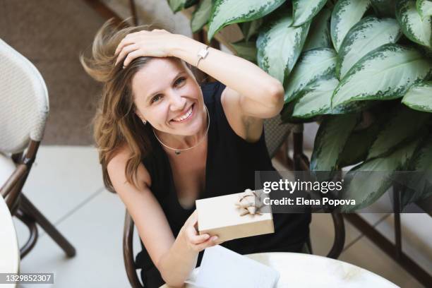 portrait of young confidence woman holding craft gift box in the cafe, smiling and looking at the camera - freedom of expression is a right and not granted stock pictures, royalty-free photos & images