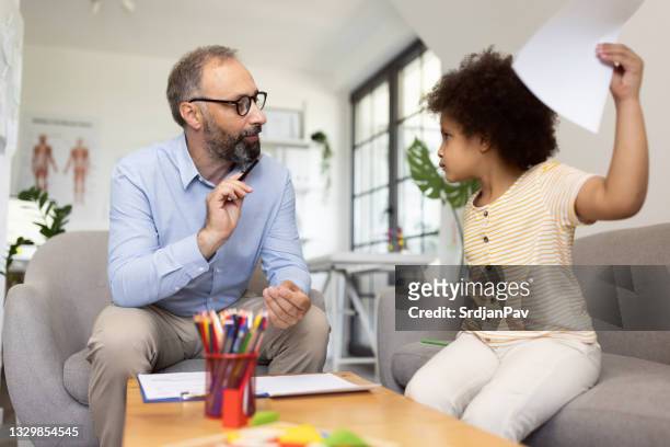 child psychologist talking with angry little girl in the office - child psychologist stock pictures, royalty-free photos & images