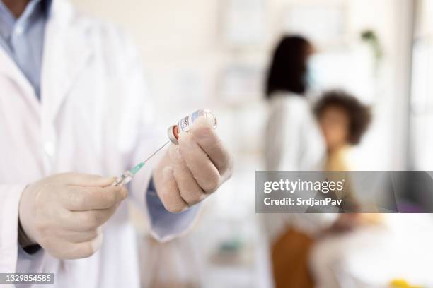 doctor´s hand with protective gloves fills syrgine with vaccine - zwarte handschoen stockfoto's en -beelden