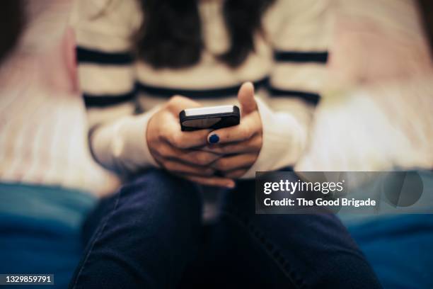 close up of teenage girl in bedroom using smart phone - teenager smart phone foto e immagini stock