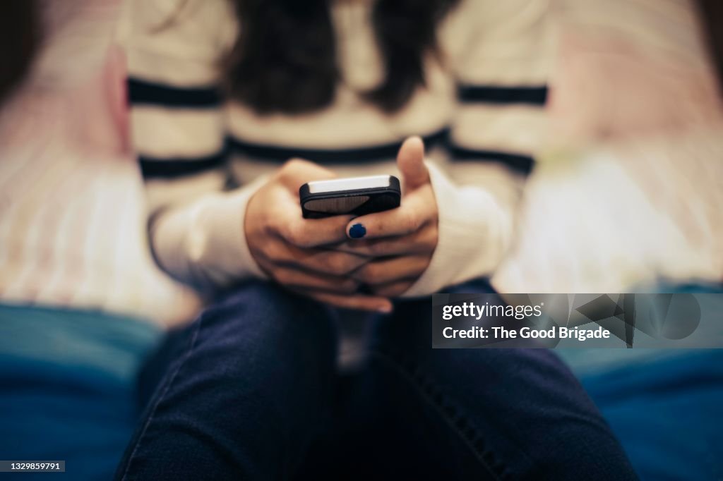 Close up of teenage girl in bedroom using smart phone