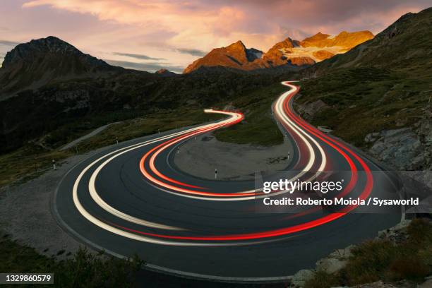 car trails lights on mountain road, switzerland - lichtspur stock-fotos und bilder