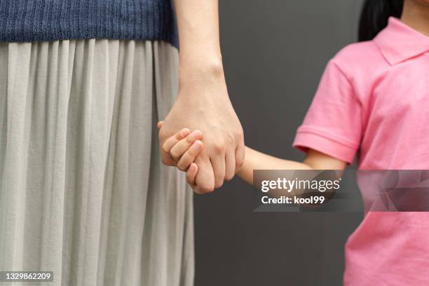 mother and daughter hand holding on gray background - school life balance stock pictures, royalty-free photos & images