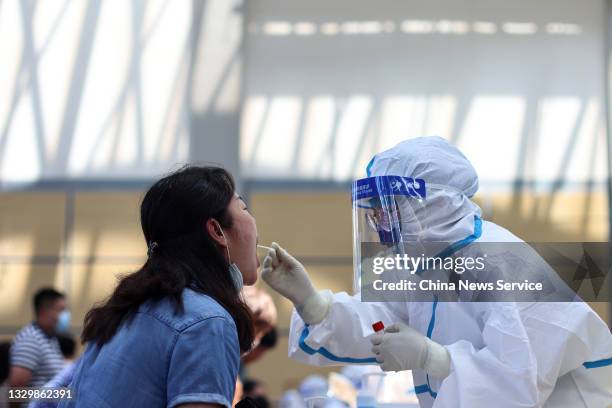Medical worker collects a throat swab from a local resident for nucleic acid testing at Jiangning Sports Center on July 21, 2021 in Nanjing, Jiangsu...