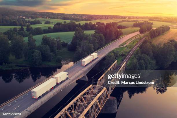 trucks driving through a countryside landscape at sunset - aerial forest stockfoto's en -beelden