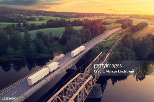 trucks driving through a countryside landscape at sunset - bouwwerk stockfoto's en -beelden