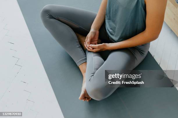 femme anonyme faisant de la pratique du yoga sur le sol de sa chambre - hand on knee stock photos et images de collection