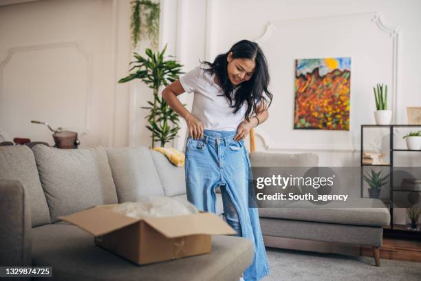 frau erhielt ein paket zu hause - trying on stock-fotos und bilder