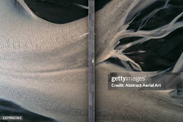 car driving over a bridge crossing a braided river seen from directly above, iceland - aerial view landscape stock pictures, royalty-free photos & images