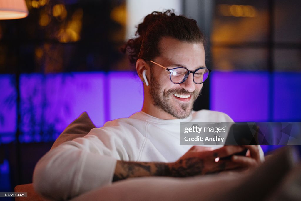 Man texting on mobile phone while relaxing at home late at night