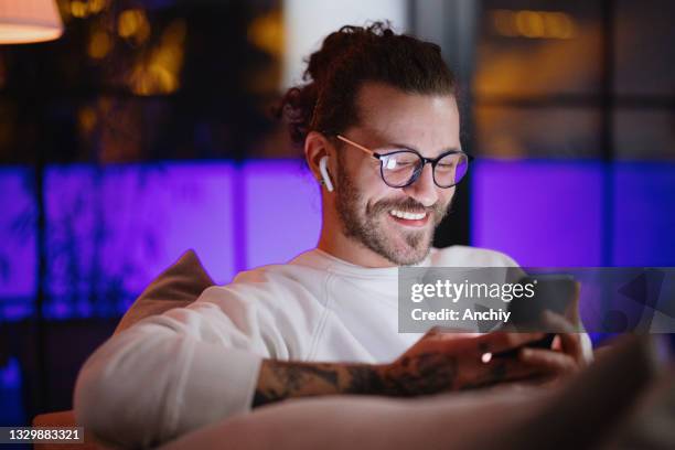 man texting on mobile phone while relaxing at home late at night - covid dating stock pictures, royalty-free photos & images