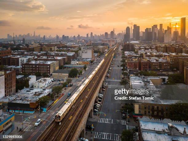 zug passiert sunnyside queen während des sonnenuntergangs in new york, usa - queens stad new york stock-fotos und bilder