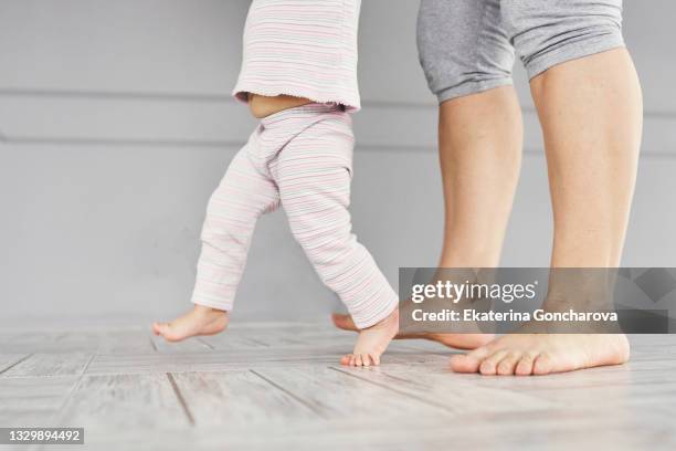 close-up of the legs of a mother and a 1-year-old daughter starting to walk. - start of year stock pictures, royalty-free photos & images