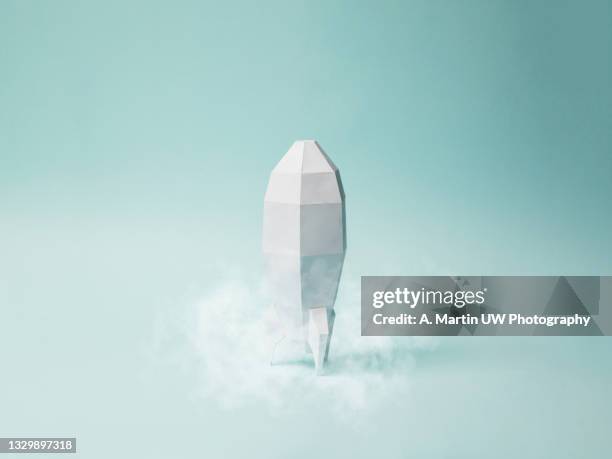 space rocket made of paper isolated on a light blue background. paper craft.  concept of space travel. space race. - first time stockfoto's en -beelden