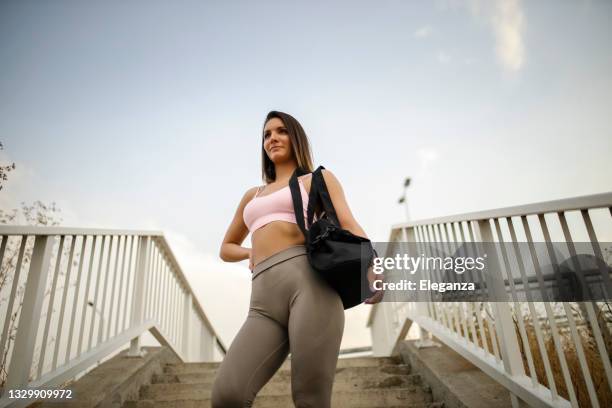 donna che porta a casa la sua borsa sportiva dopo l'allenamento - carrying sports bag foto e immagini stock