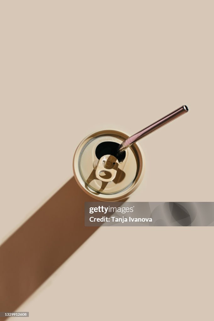 Beige aluminum drink can with reusable stainless steel straws on beige background. Minimal art still life. Zero waste, plastic free concept.