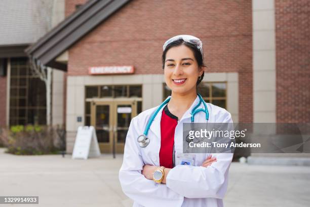 young woman medical professional standing outside emergency room of hospital - red stethoscope stock pictures, royalty-free photos & images